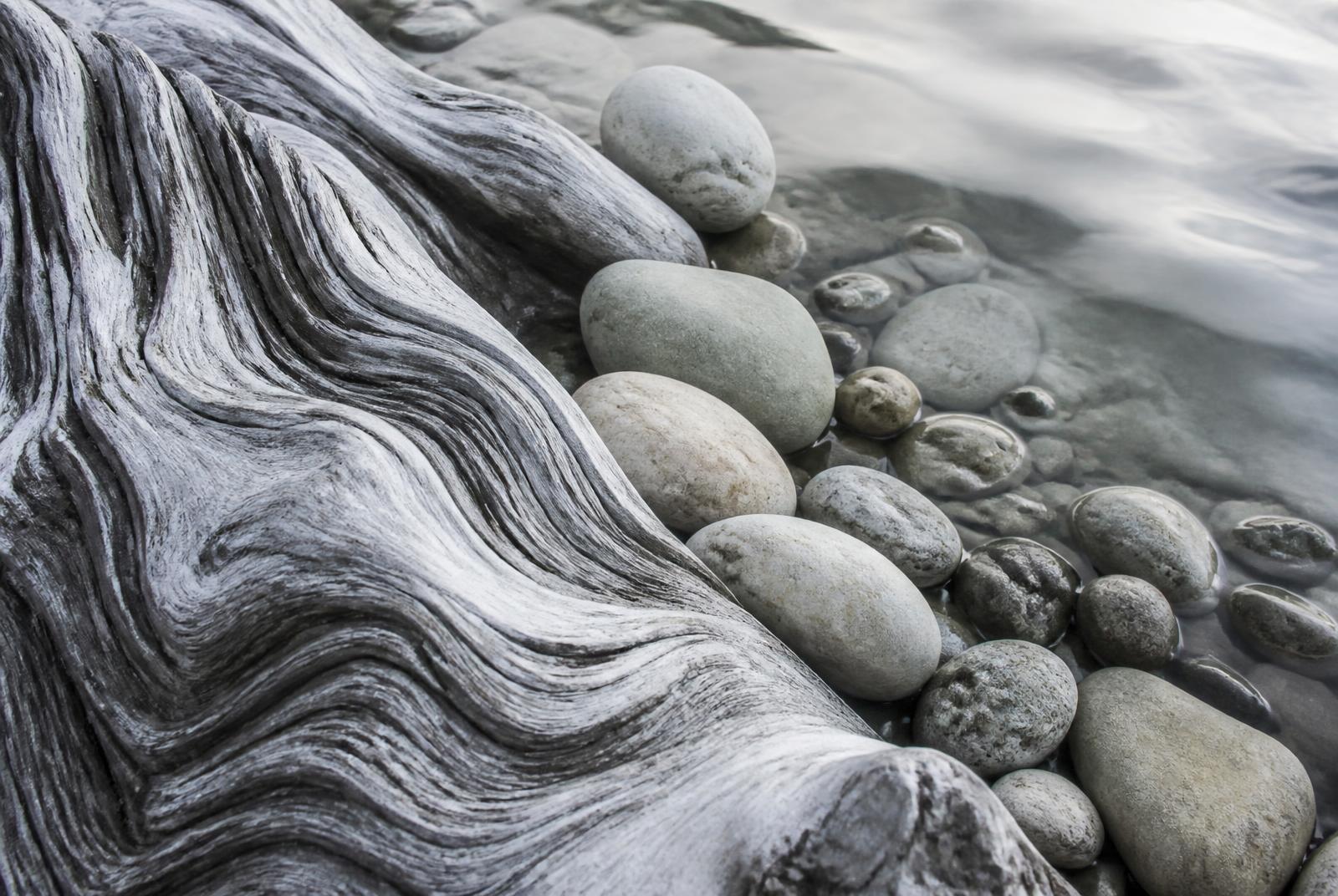 Weathered driftwood and smooth stones at the water's edge